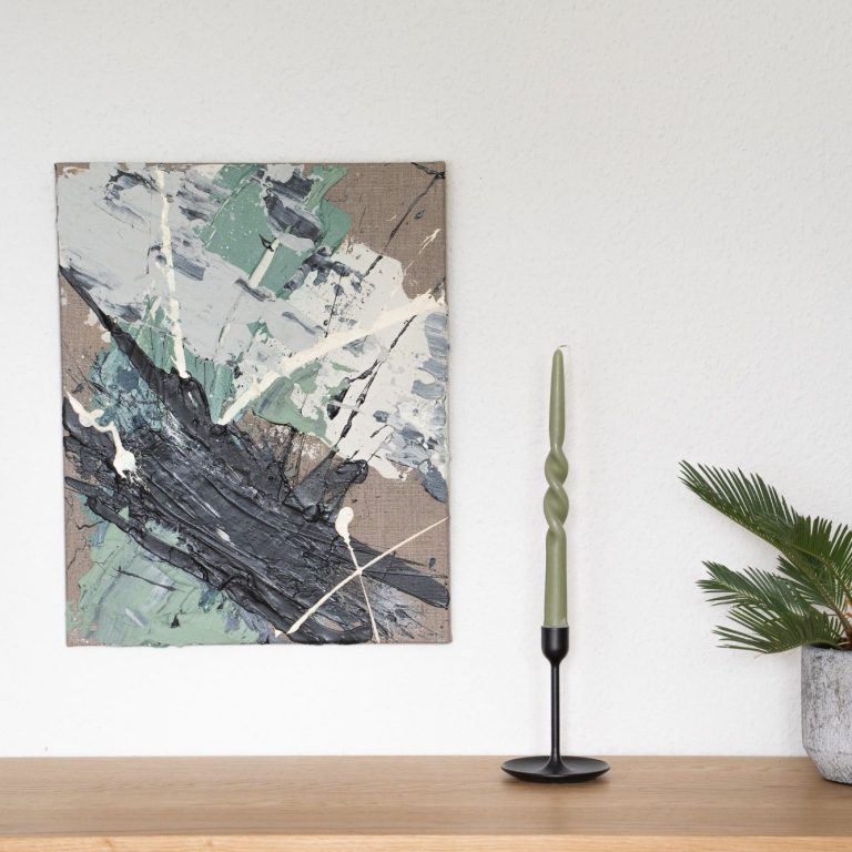 Abstrakte Malerei in sanften Farben neben einer vertikalen, minimalistischen Kerze.