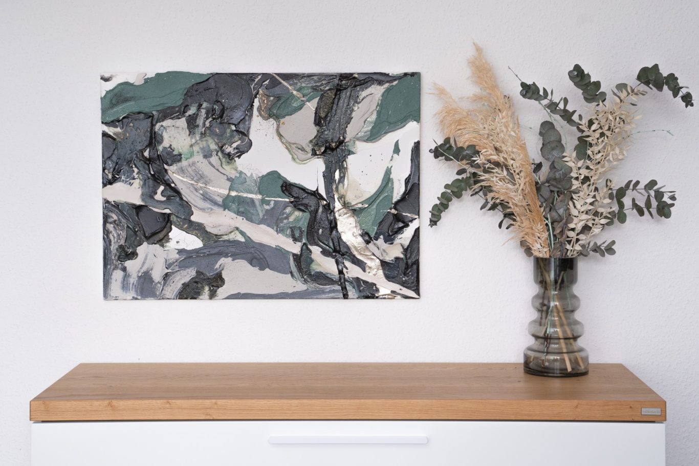 Petroleige, 50 x 70 cm, 600€* Abstrakte Wandkunst in sanften Grüntönen neben einer Vase mit Trockenblumen auf einem Tisch.