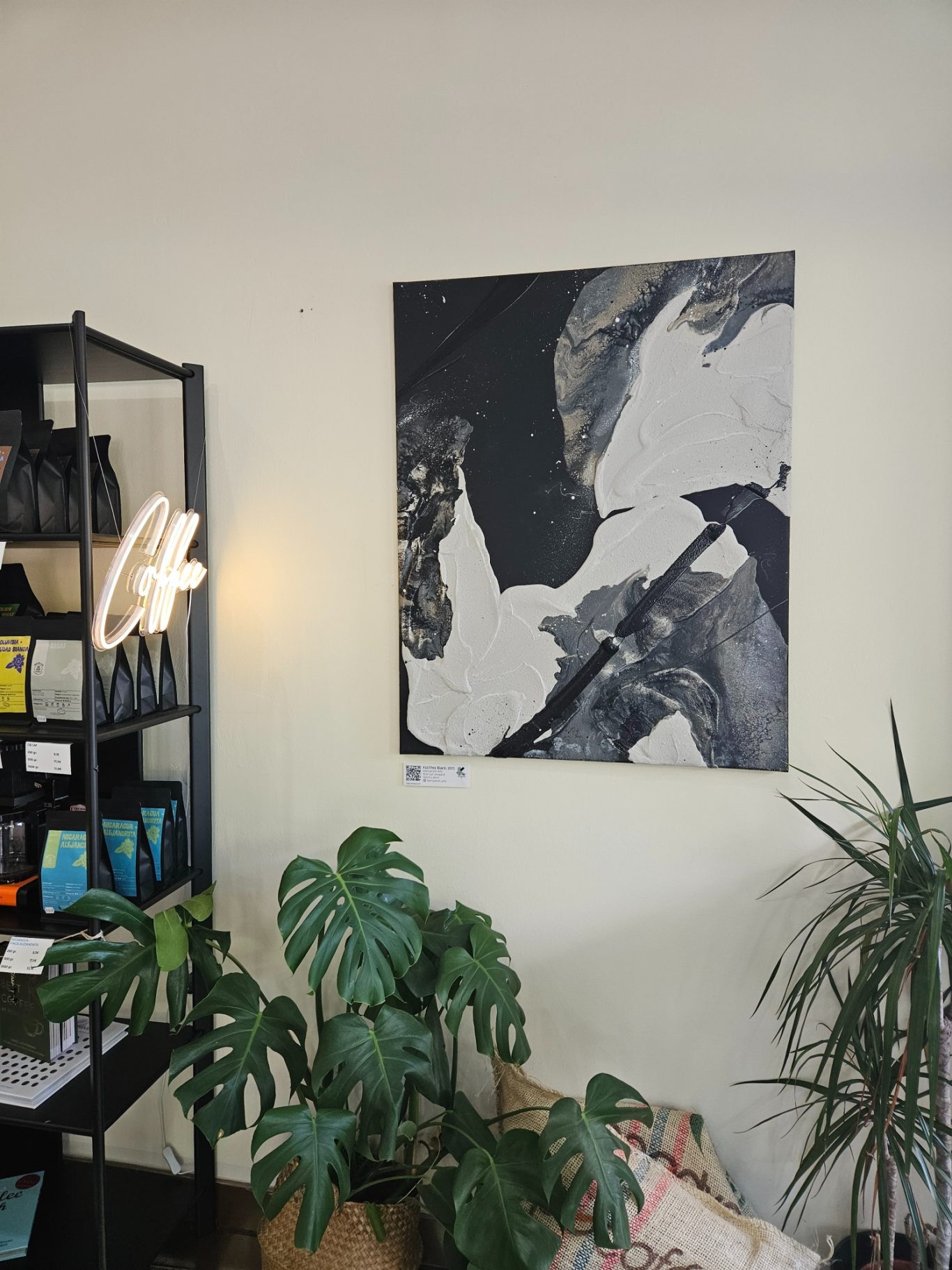 Kalithea Black, 80 x 100 cm, 1000€* Abstrakte Schwarz-Weiß-Kunst auf einer Wand, umgeben von Pflanzen und Regalen.