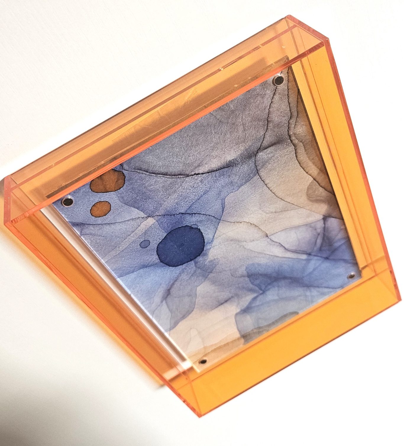 Laubflug, 65€* Orangene Box mit einer transparenten Folie und blauen, bunten Musterungen im Inneren.