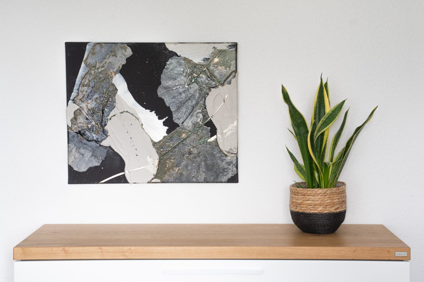 Mud Kalithea, 50 x 60 cm, 400€* Abstraktes Kunstwerk in Schwarz, Weiß und Grau, daneben Topfpflanze auf Holzregal.